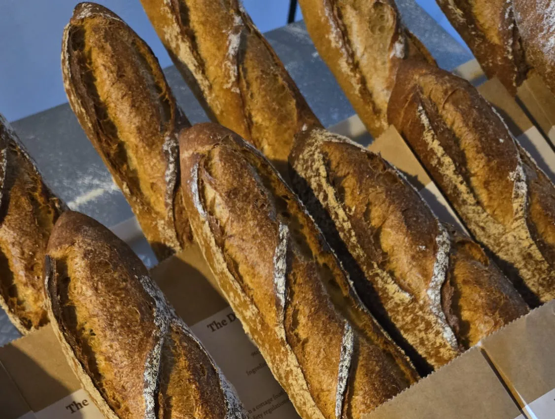 Golden sourdough baguettes with flour-dusted crusts cooling on a bakery table